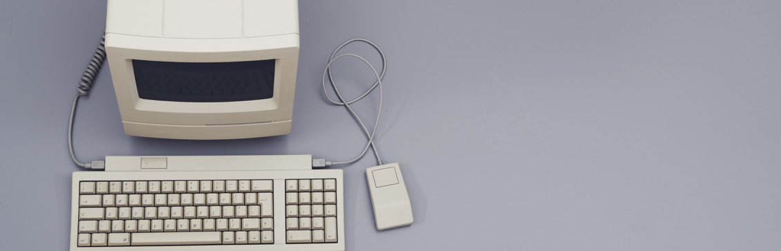 A vintage personal computer with monitor, keyboard, and mouse on a plain background