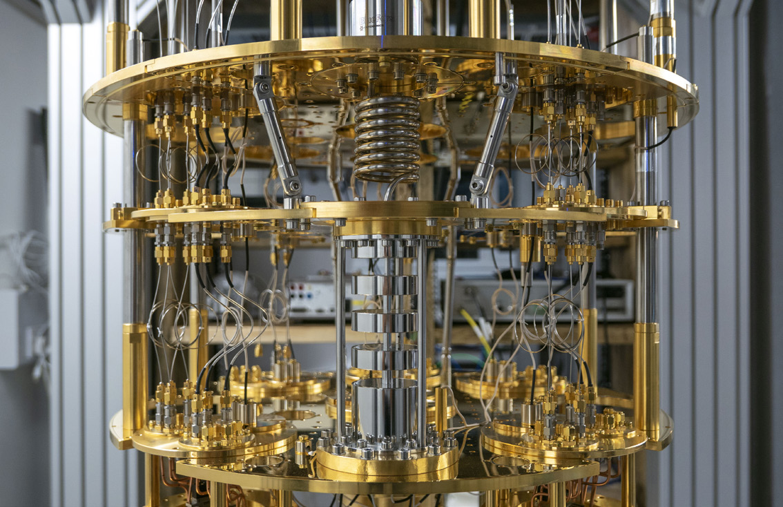 A photograph of a gold-plated dilution refrigerator with a quantum processor at the bottom.