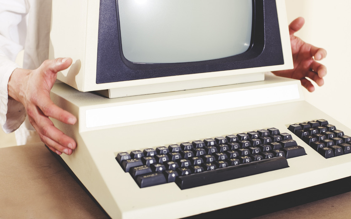 Hands placing a vintage desktop computer on a desk