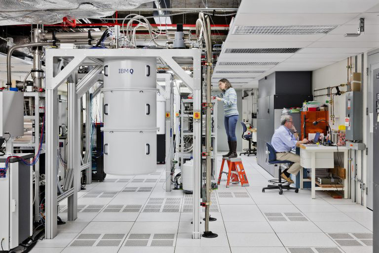 Researchers working beside a dilution refrigerator in a quantum computing lab