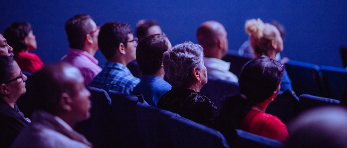 An audience watching a presentation in a darkened auditorium
