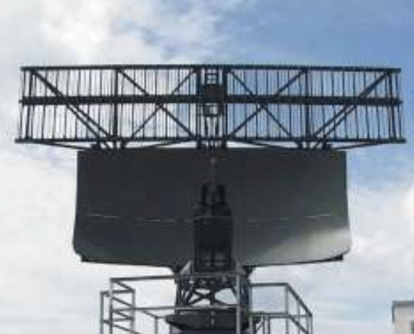 Monopulse secondary radar antenna mounted atop a primary radar parabolic reflector.