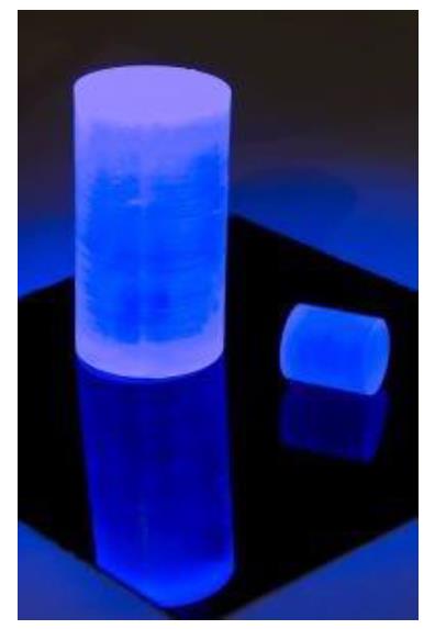 Photograph of plastic scintillator pieces glowing blue under ultraviolet stimulation.