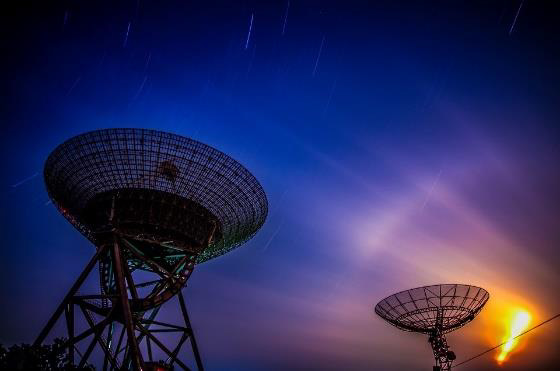 Large radio telescope dishes against a night sky